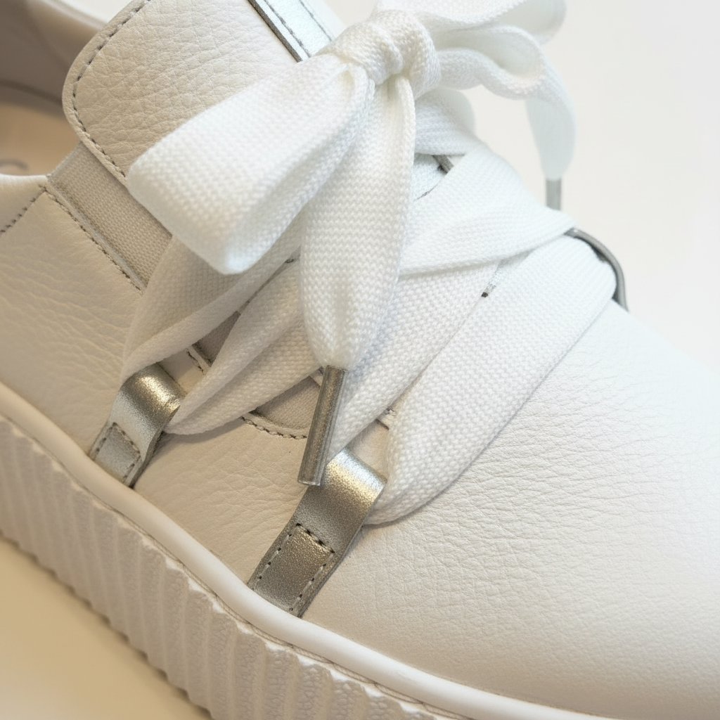 White sneaker with a decorative bow on a light background