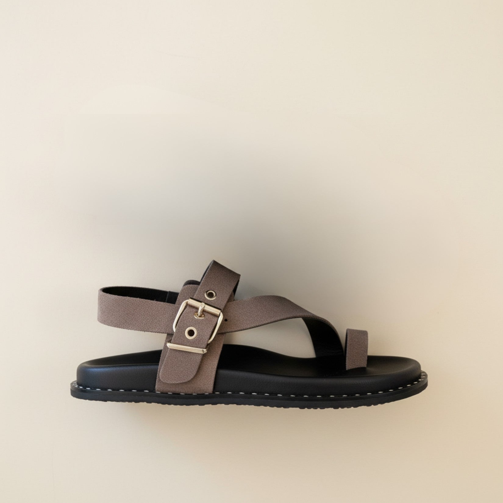 Brown sandal with a buckle on a beige background