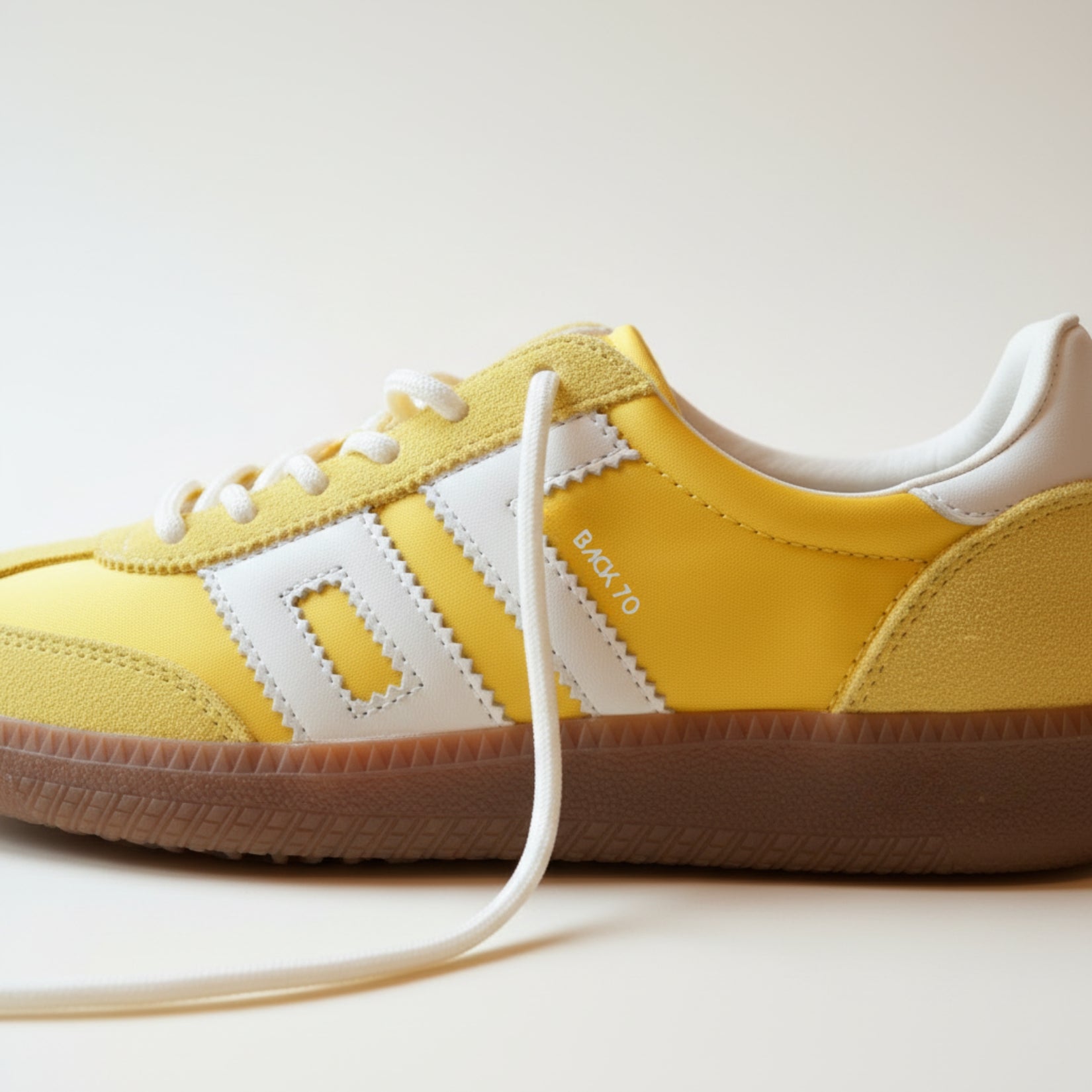 Yellow sneaker with white laces on a light background
