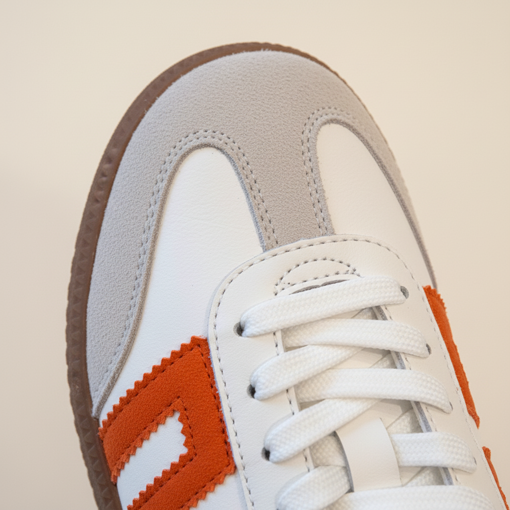 Close-up of a sneaker with orange and brown accents on a beige background