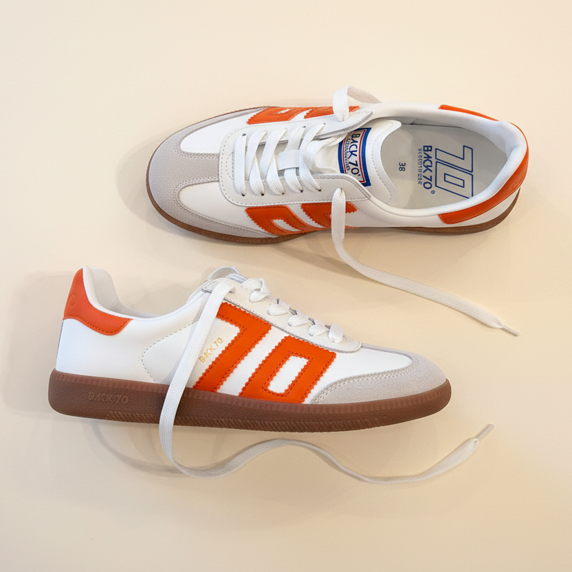 Pair of white and orange sneakers on a beige background