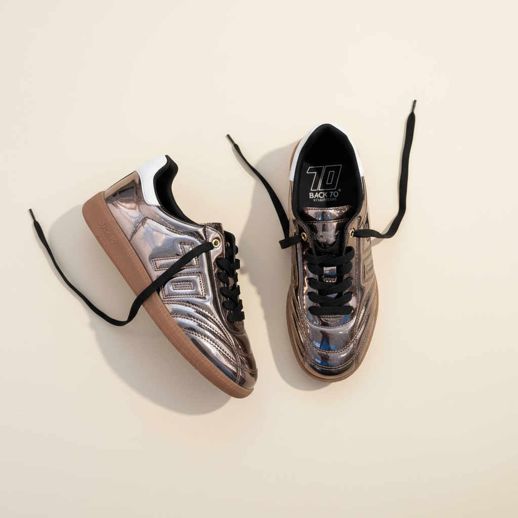 Pair of metallic sneakers with black laces on a beige background
