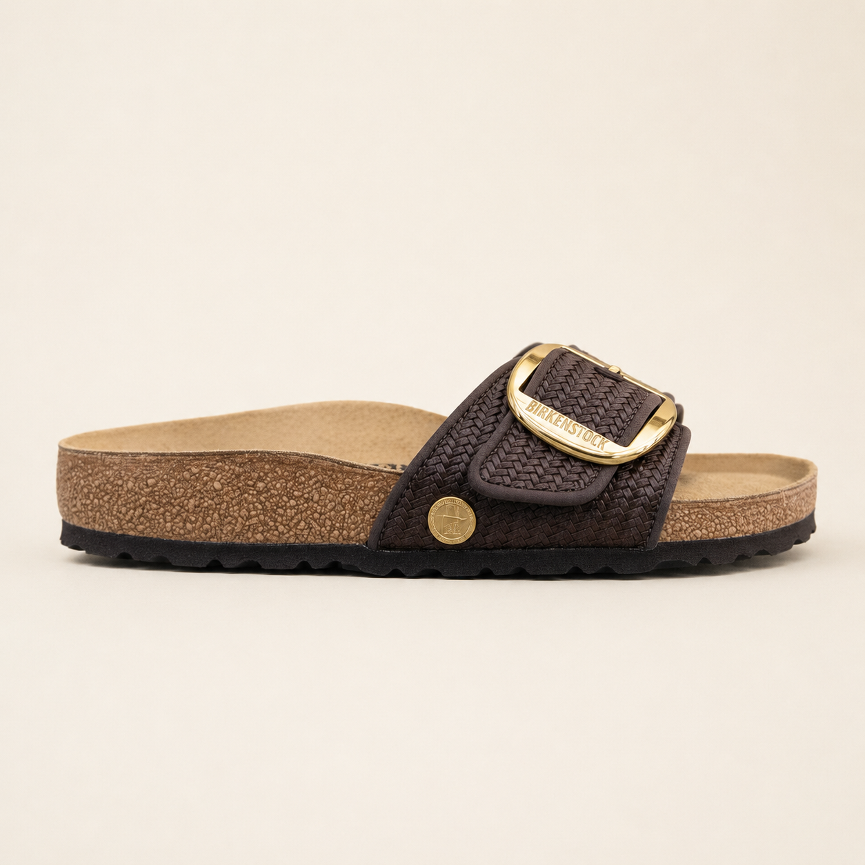 Brown sandal with gold buckle on a beige background