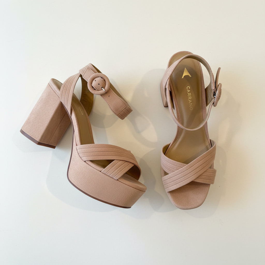 Pair of beige high-heeled sandals on a textured surface