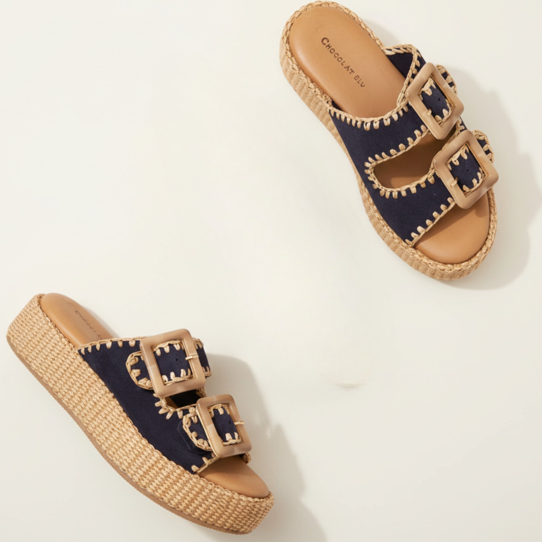 Pair of sandals with wicker sole and navy uppers on a light background