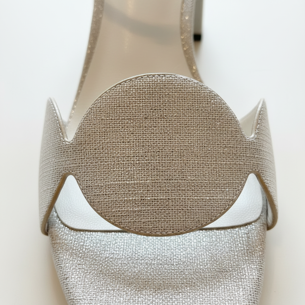 Close-up of a silver high-heeled shoe with decorative elements on a white background