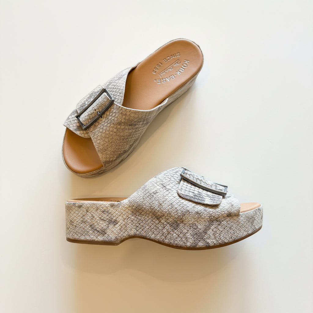 Pair of patterned sandals with buckles on a textured surface