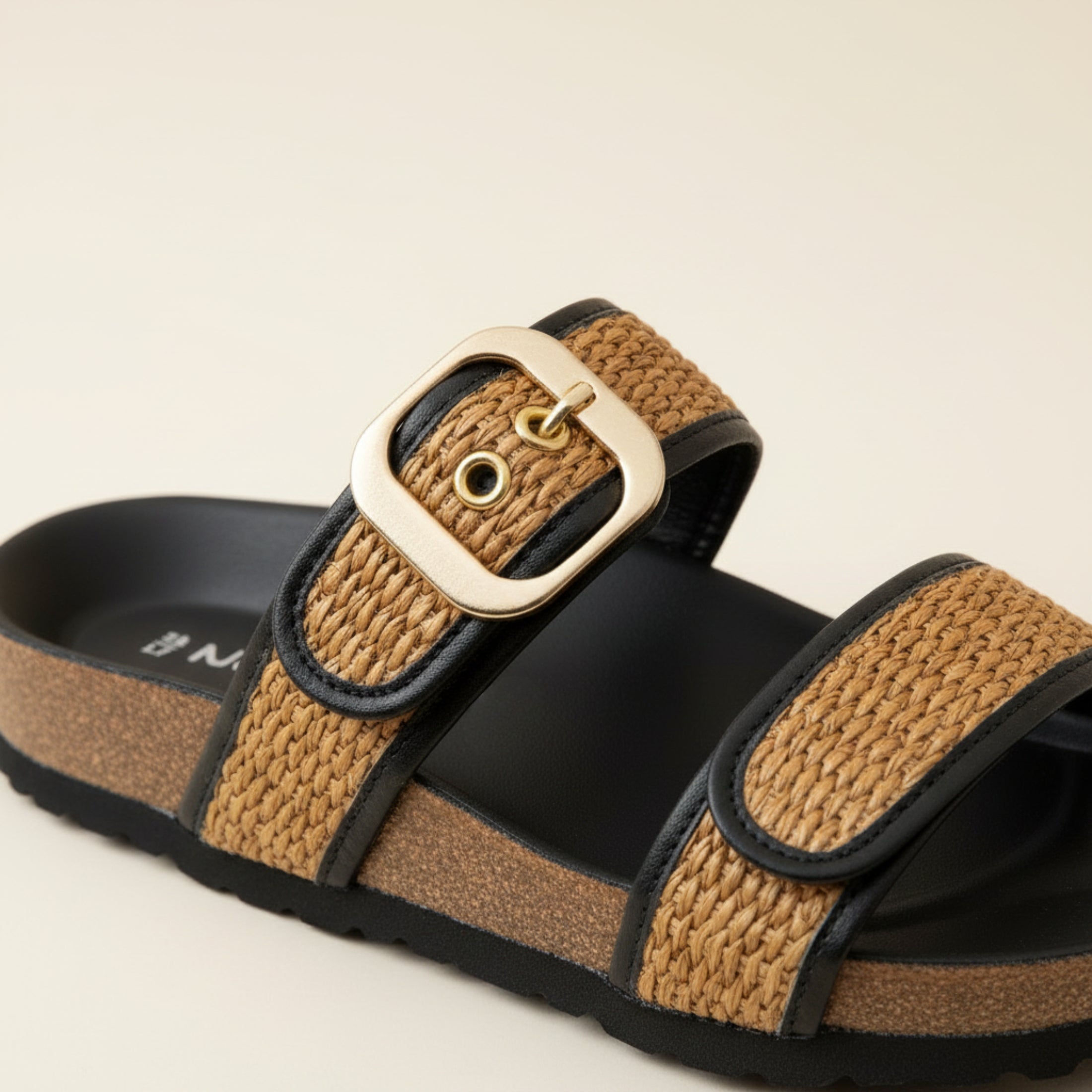 Brown sandal with a gold buckle on a beige background