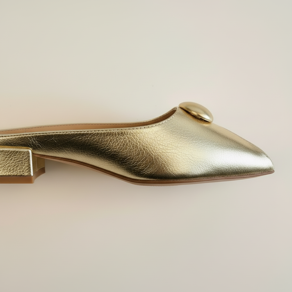 Gold flat shoe on a light beige background