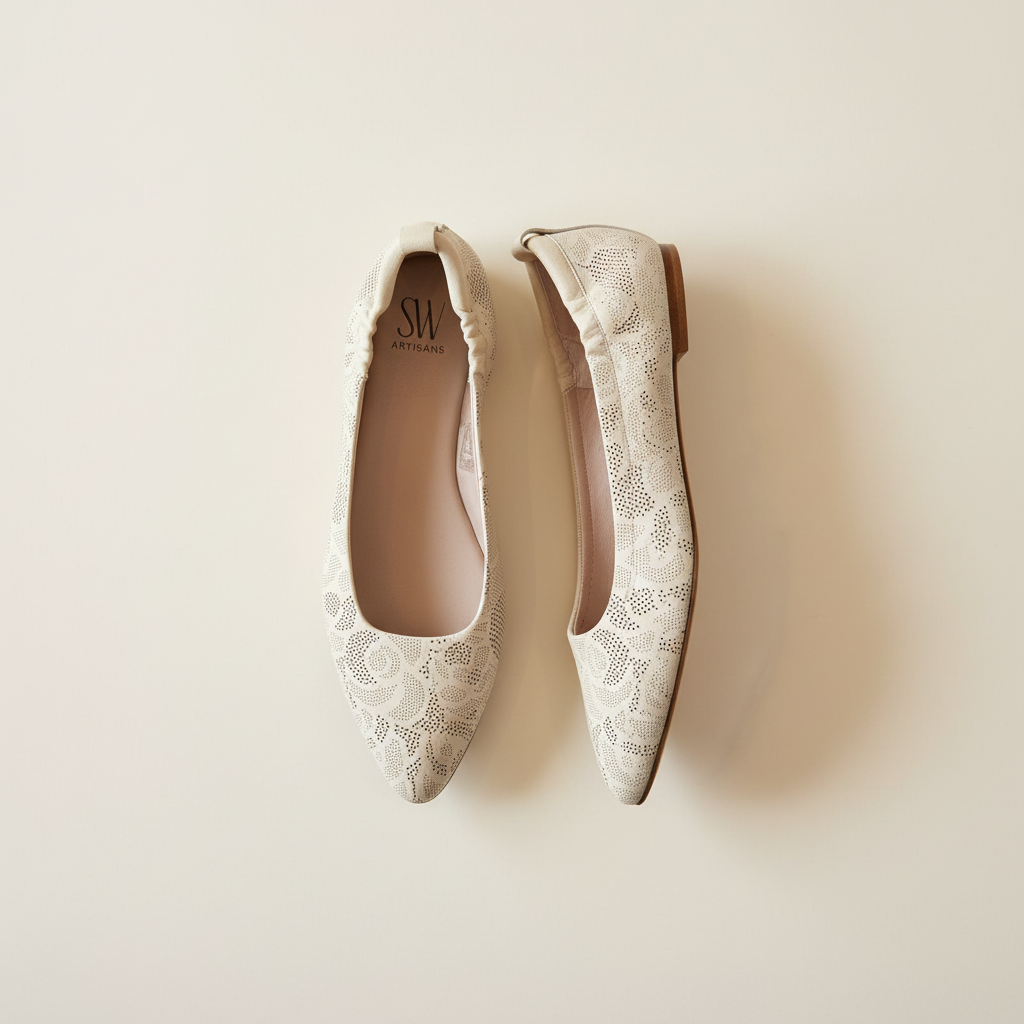 Pair of lace-patterned flats on a beige background