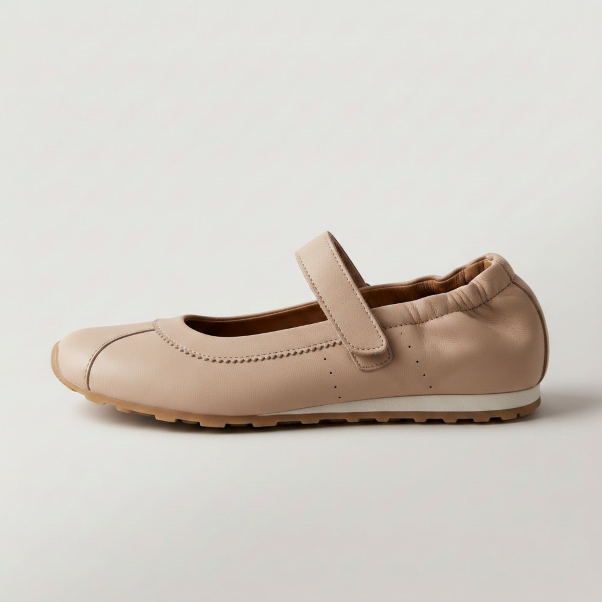 A single beige leather Mary Jane flat shoe with a hook-and-loop strap, shown in profile against a light gray background.