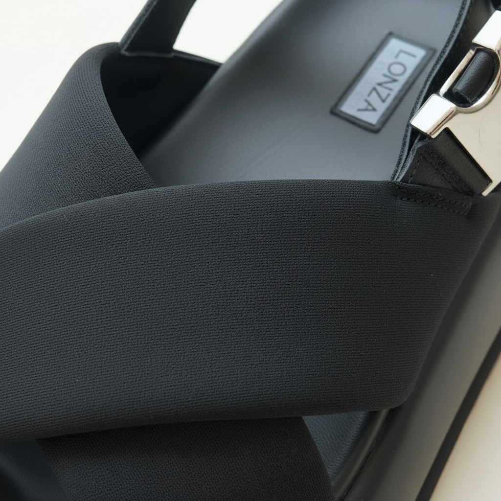 Close-up of a black handbag with a visible brand logo on a light background