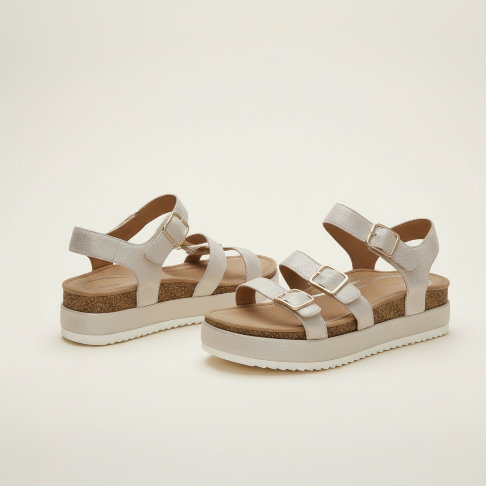 Pair of white sandals with cork platforms on a light beige background