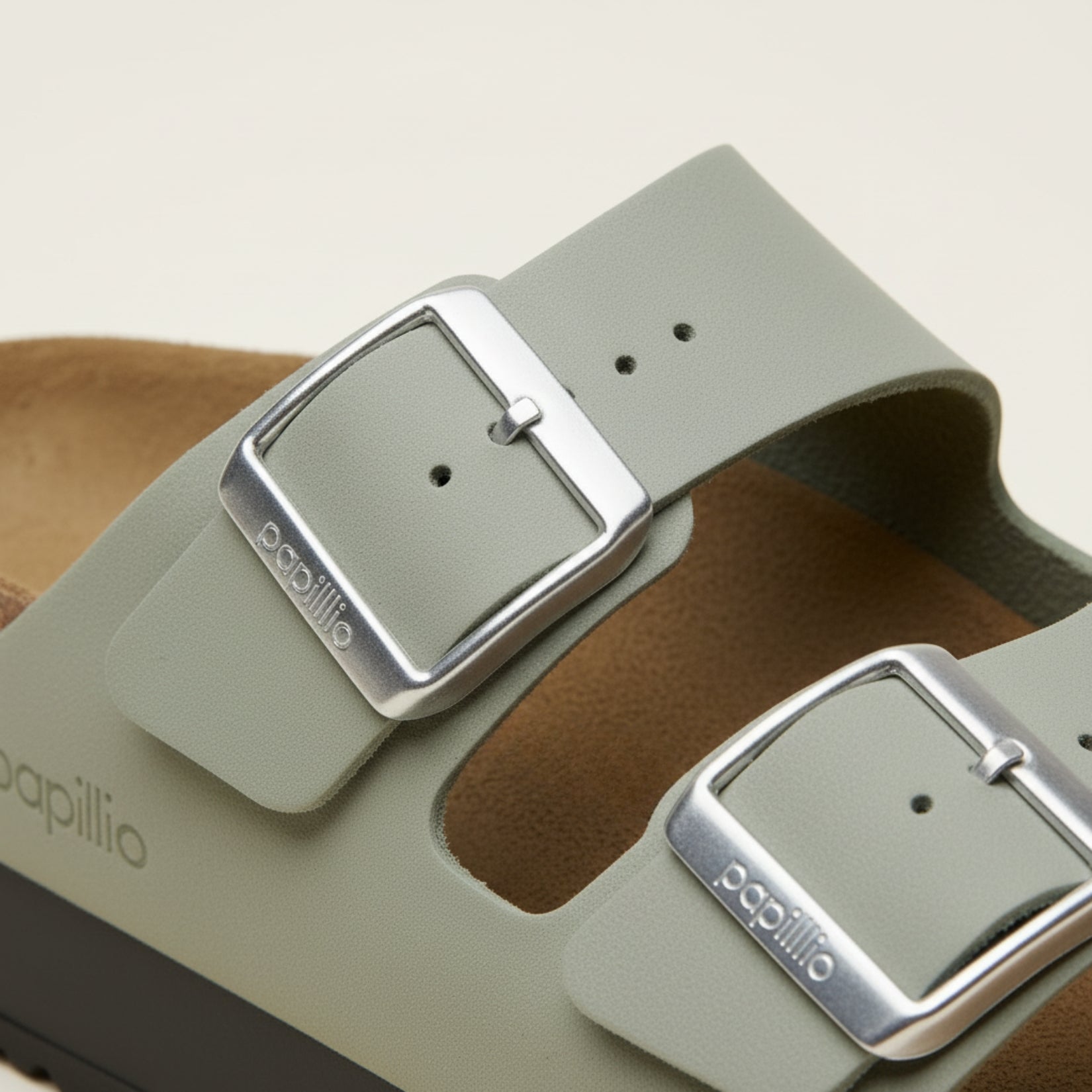 Close-up of a sandal with a metallic buckle and 'papillio' branding.