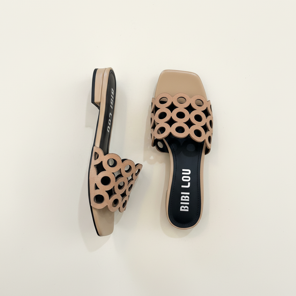 Pair of beige sandals with circular cut-out design on a light background