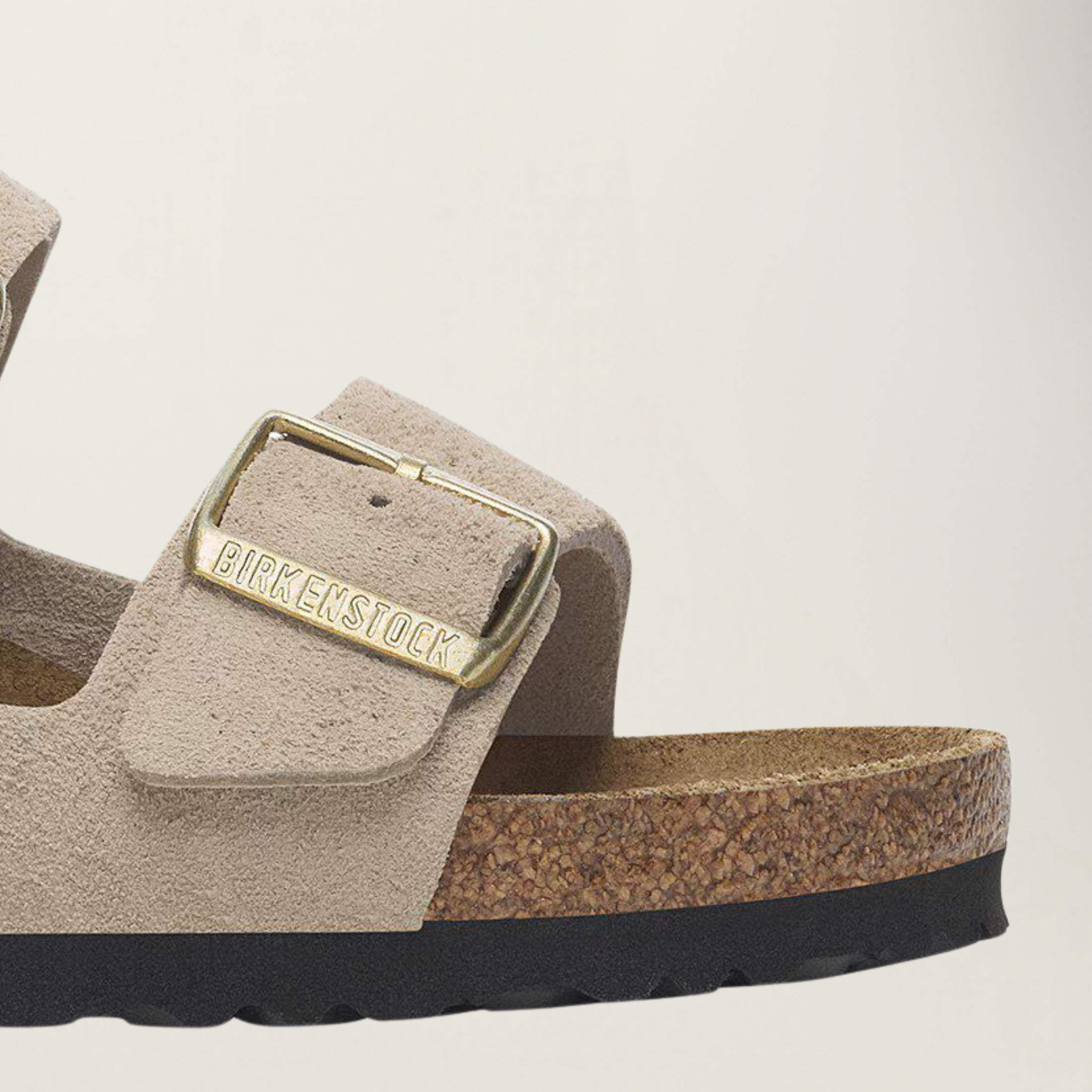 Birkenstock sandal with a gold buckle on a beige background