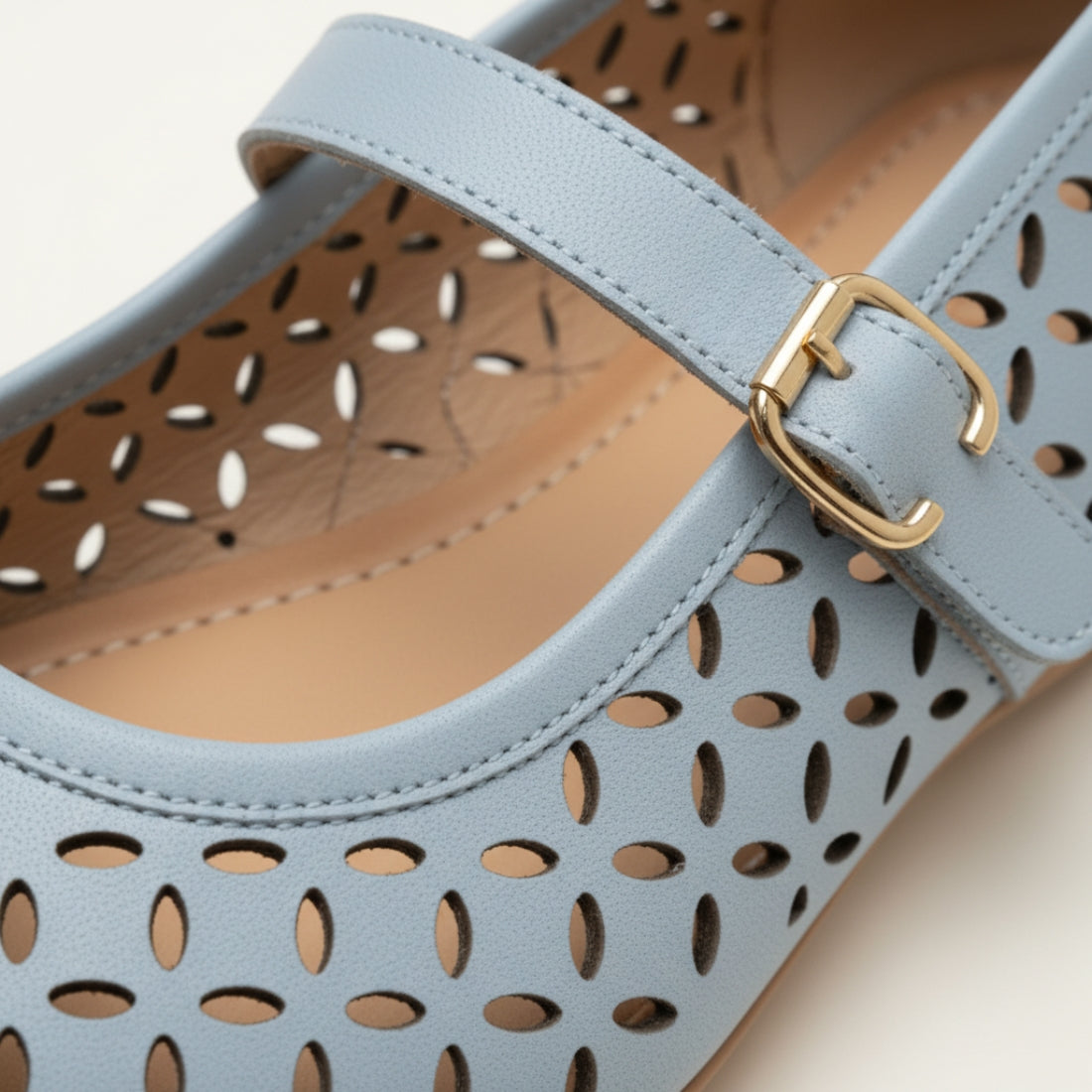 Light blue shoe with gold buckle on a beige background