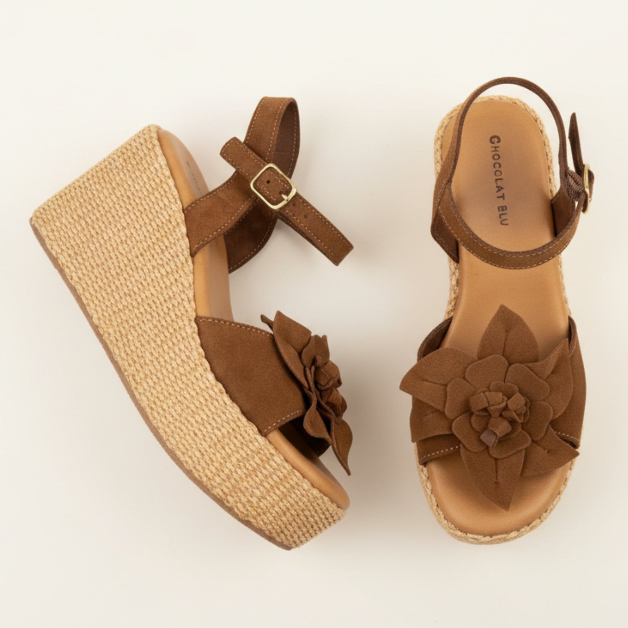 Brown wedge sandals with floral details on a beige background