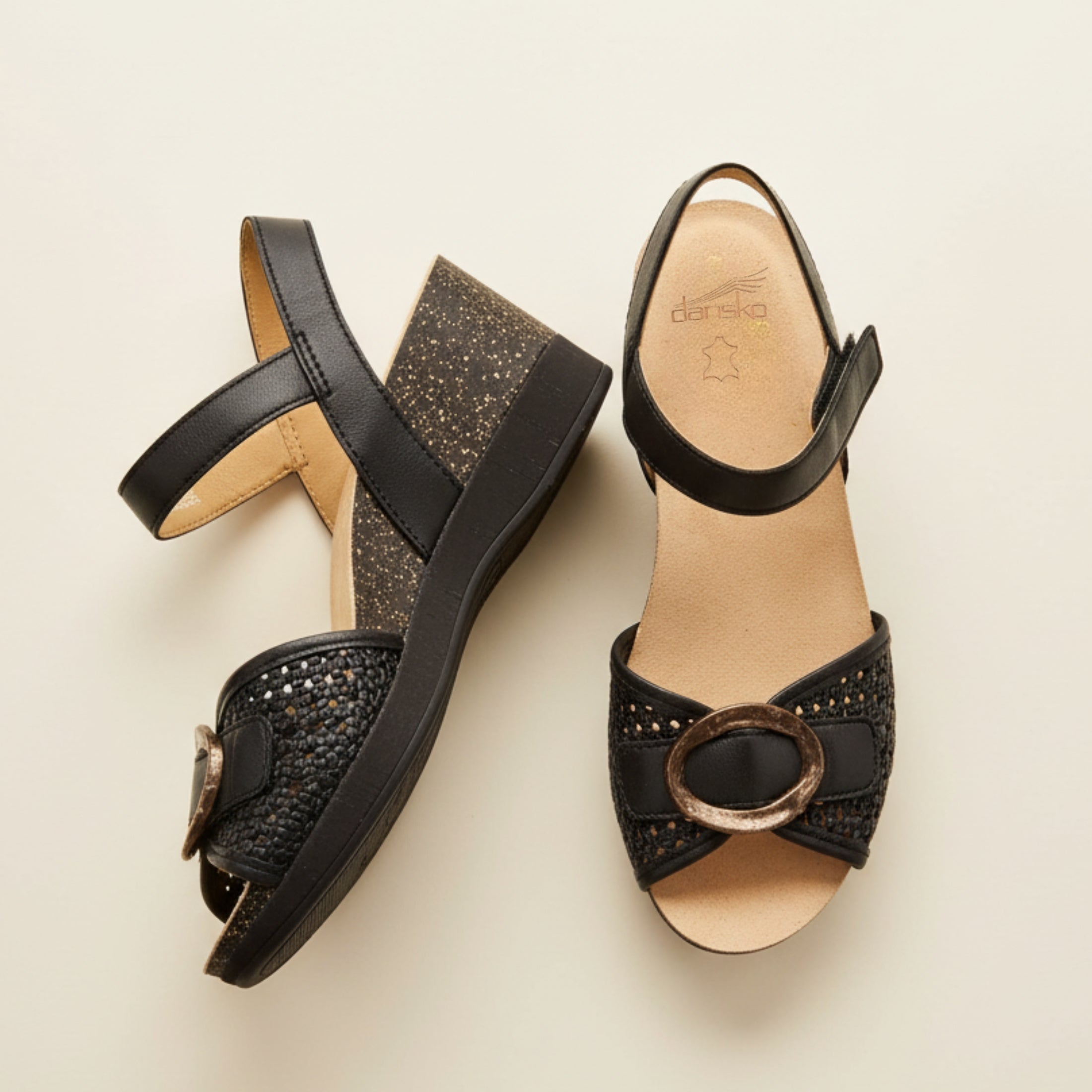 Black sandals with decorative elements on a beige background