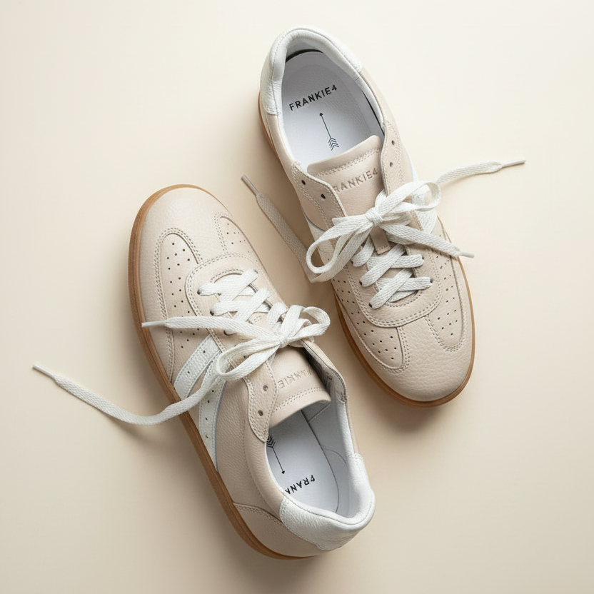 Pair of beige sneakers with white laces on a light beige background