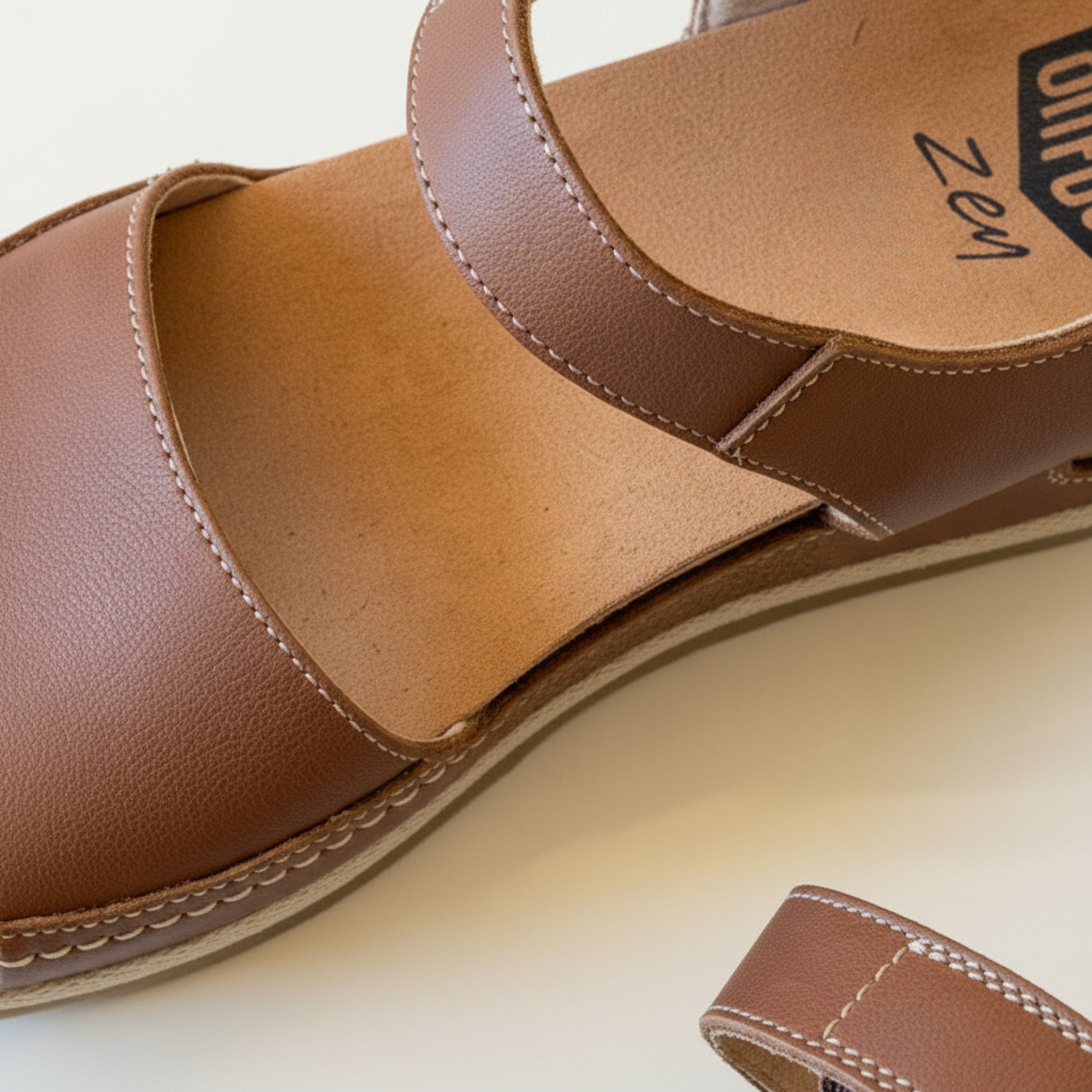 Brown sandal with 'Zen' branding on a light background
