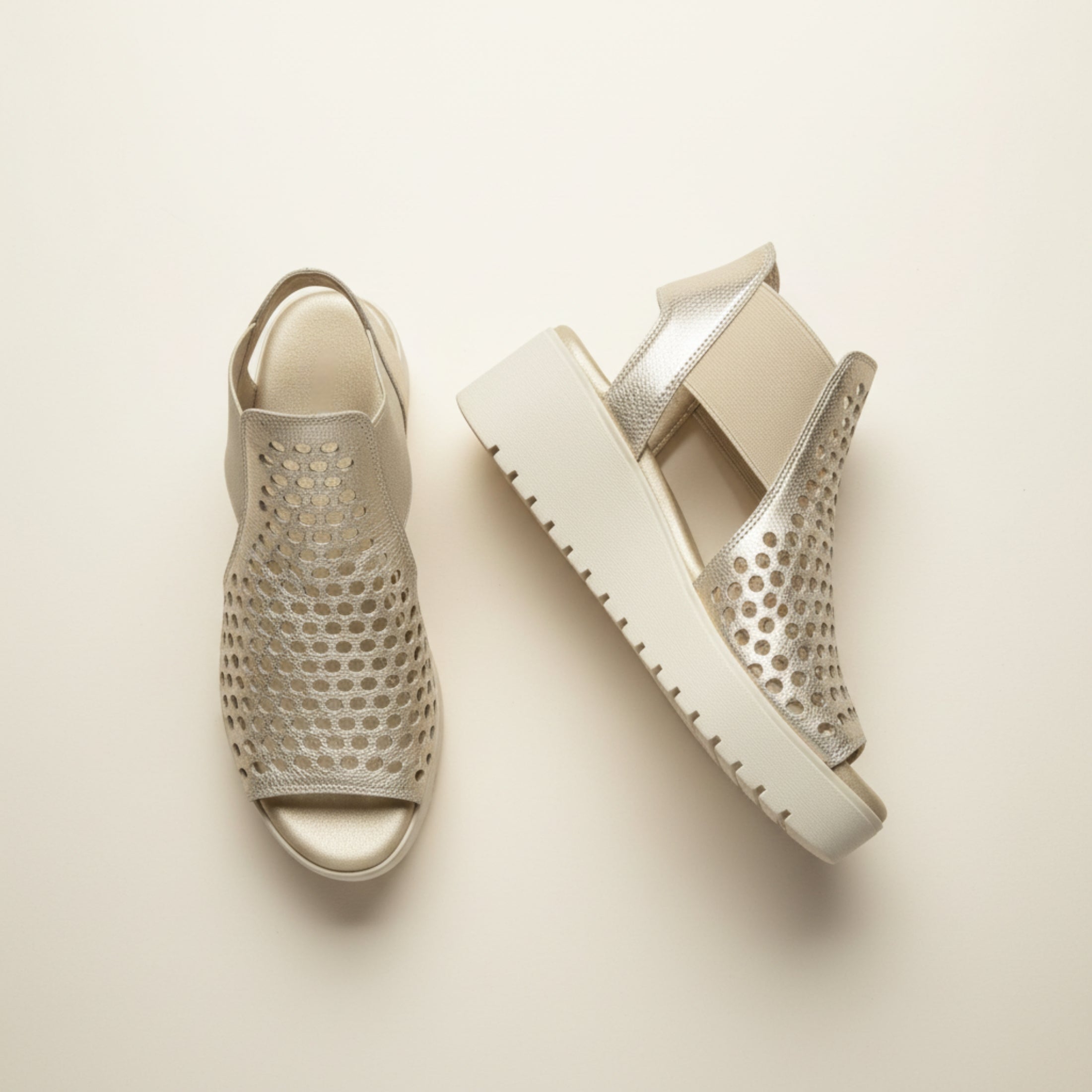 Pair of silver sandals with textured design on a beige background