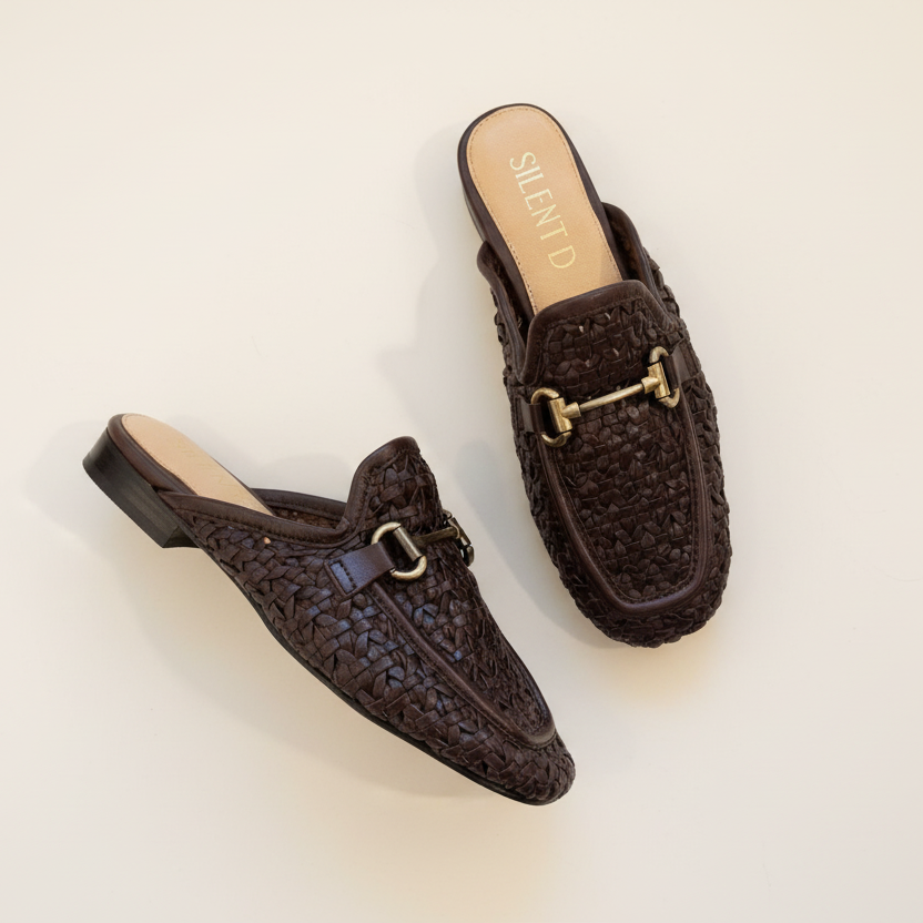Pair of brown woven loafers with gold buckles on a light beige background