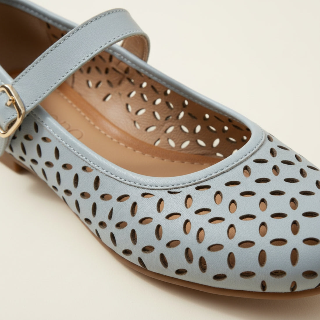 Light blue shoe with gold buckle on a beige background