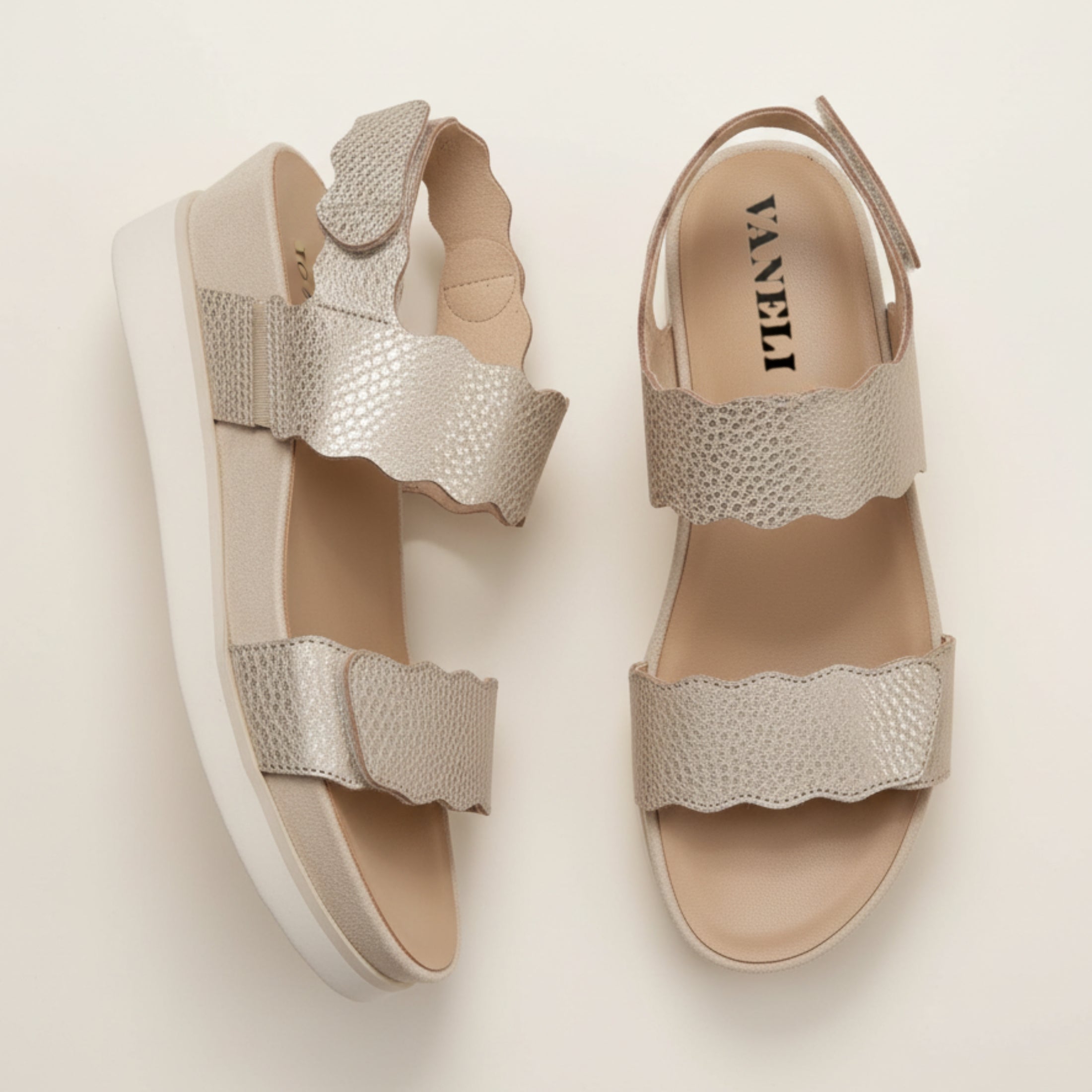 Pair of silver sandals with a textured strap on a light background