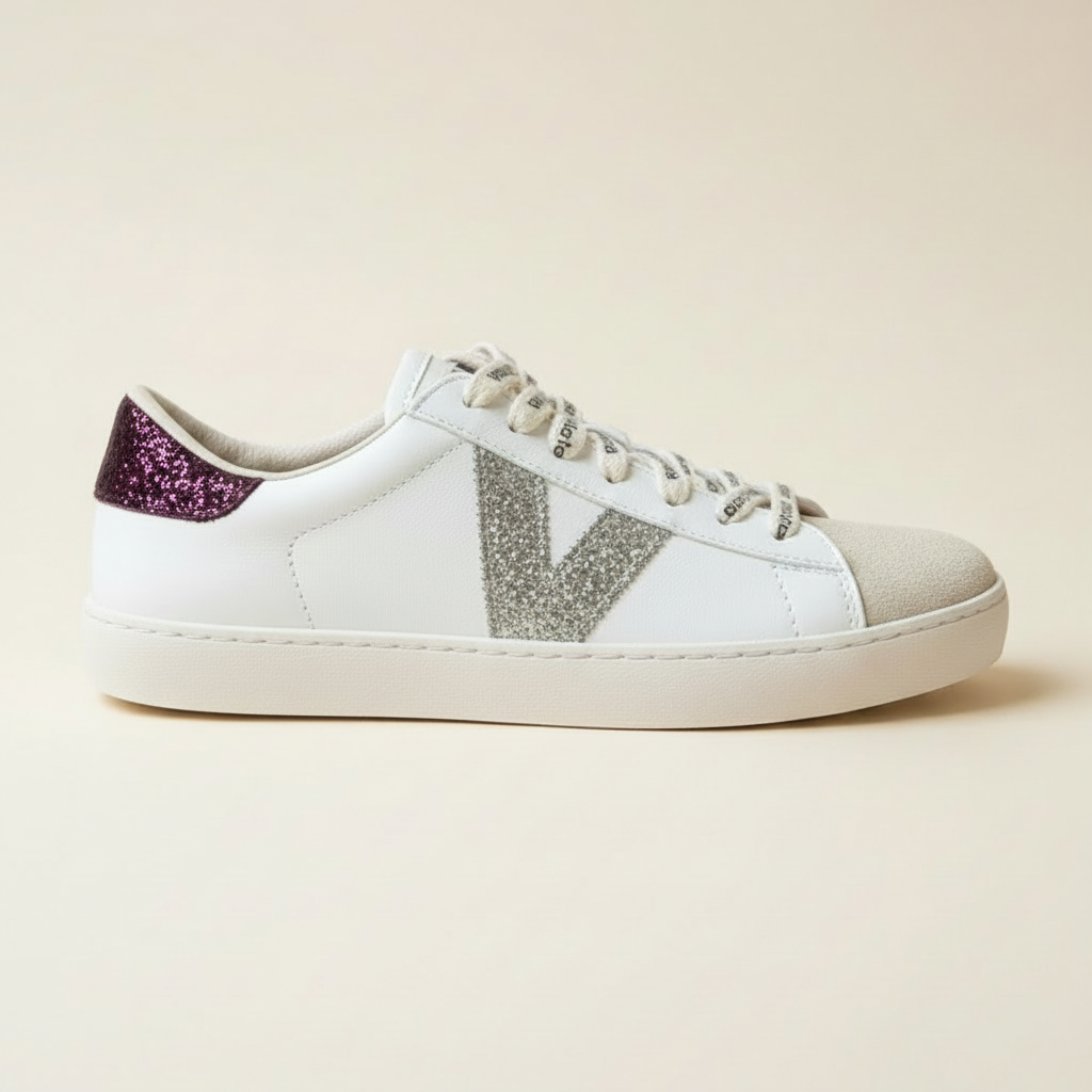 A white leather sneaker with a glittery silver V logo on the side, a purple glitter heel tab, and white laces, shown in profile against a light beige background.